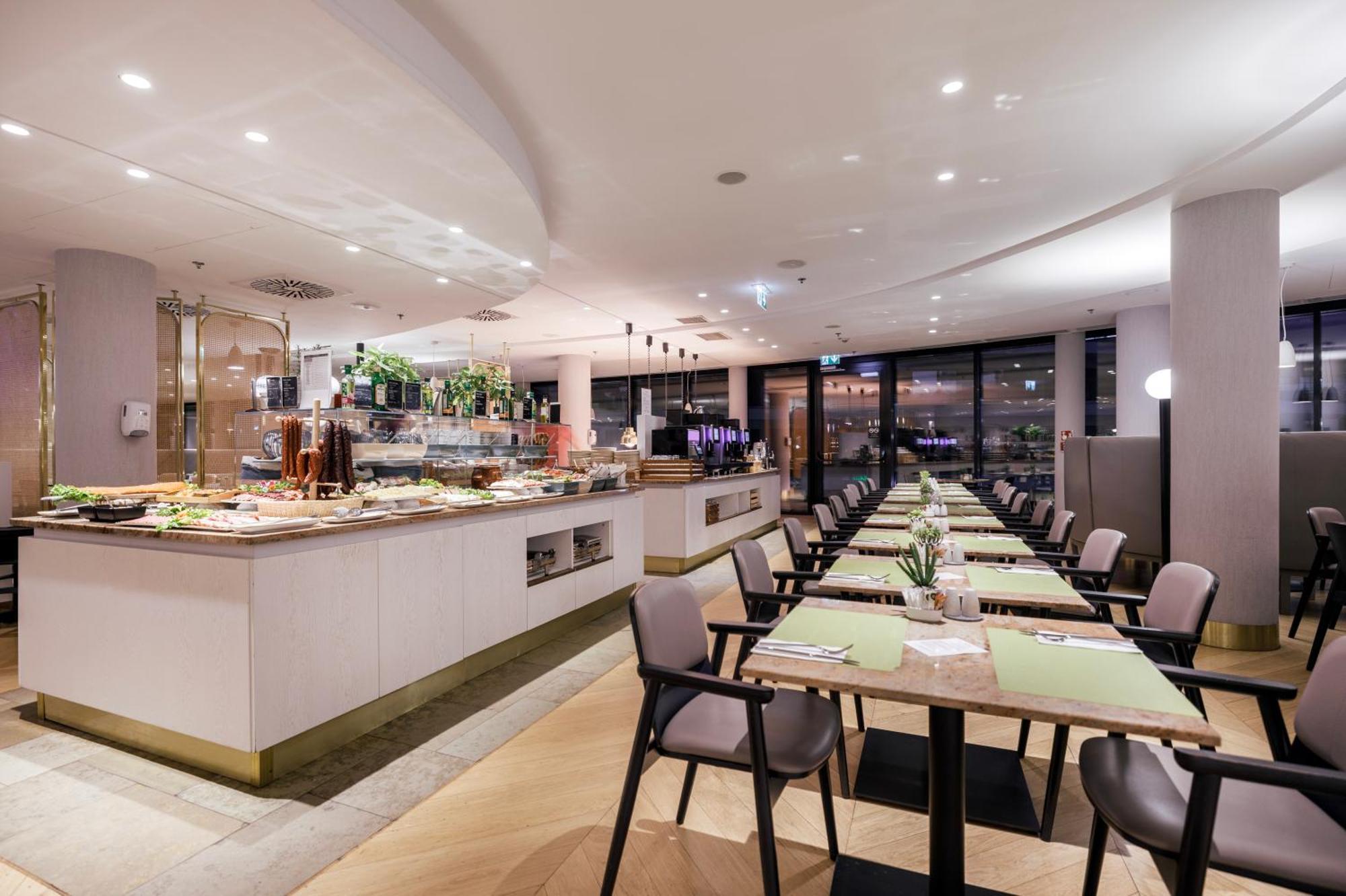 منتجع راديسون بلو سوينوجسي سفينويتشي المظهر الخارجي الصورة The photo shows a modern restaurant interior. There is a long dining table set with green placemats, and several chairs arranged around it. To the left, there is a buffet area featuring a variety of dishes and drinks, beautifully presented. The resta