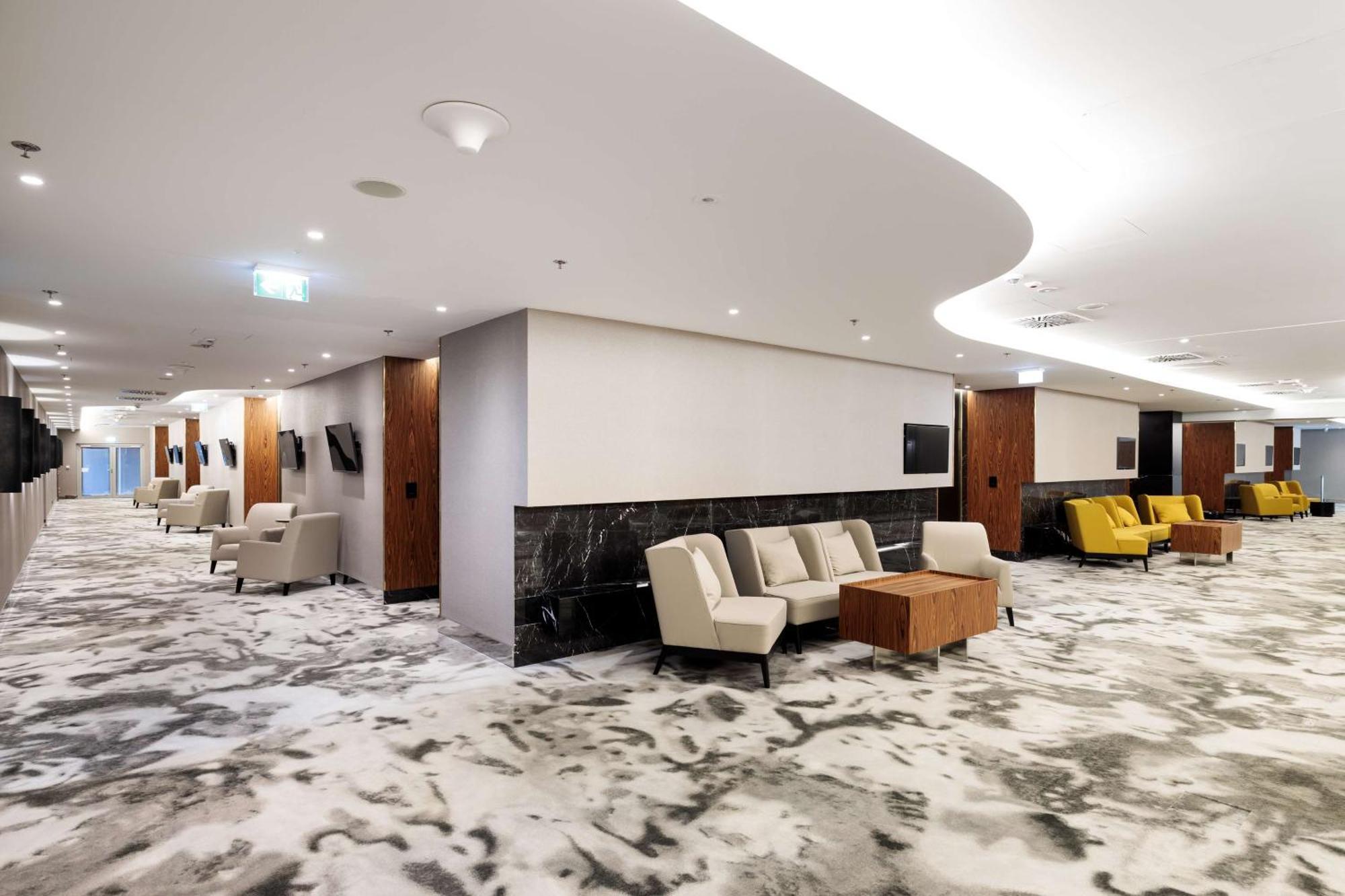 منتجع راديسون بلو سوينوجسي سفينويتشي المظهر الخارجي الصورة The photo shows a modern interior space, likely a lobby or lounge area. The flooring features a patterned carpet, and the walls are neutral in color, creating a calm ambiance. There are comfortable seating arrangements, including a group of beige cha