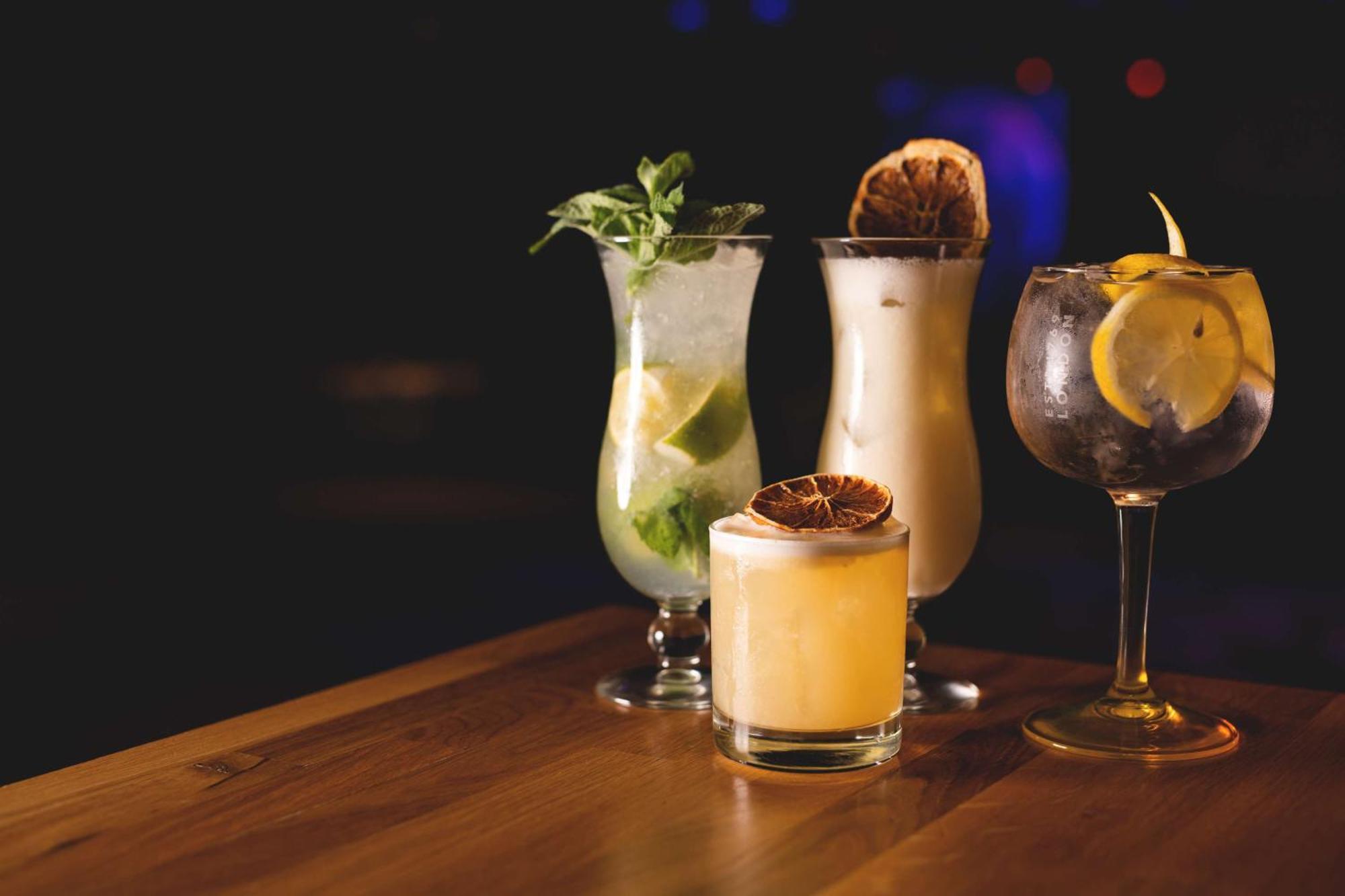 منتجع راديسون بلو سوينوجسي سفينويتشي المظهر الخارجي الصورة The photo showcases a collection of four different cocktails displayed on a wooden table. 

1. **Mojito**: A tall glass filled with lime slices, mint leaves, and a clear liquid, likely rum-based, garnished with fresh mint.
2. **Creamy Cocktail**: A s