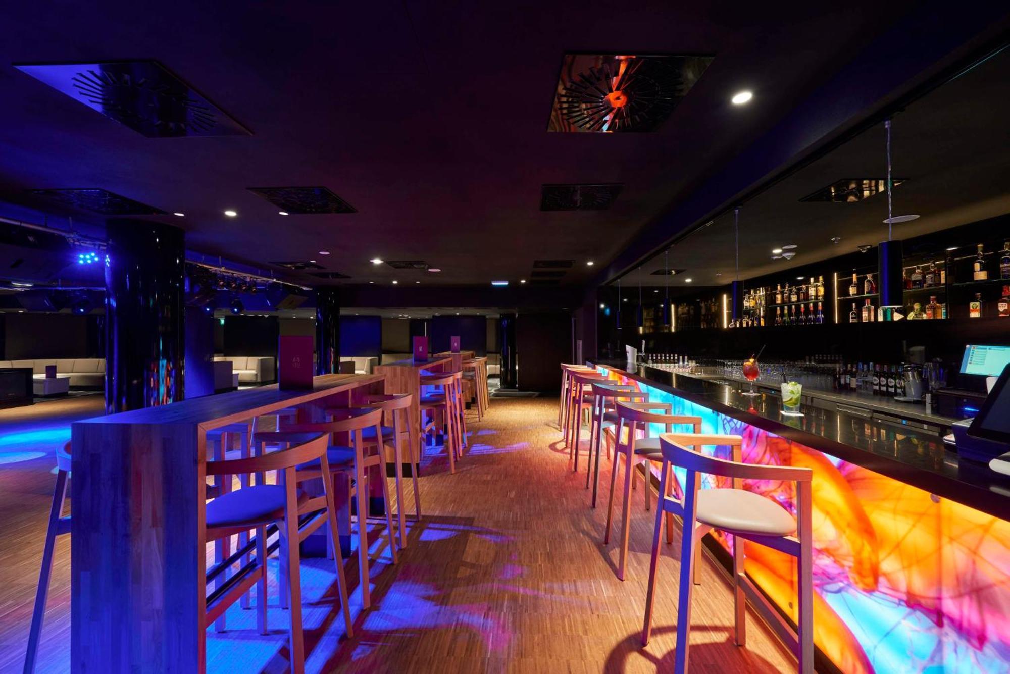 منتجع راديسون بلو سوينوجسي سفينويتشي المظهر الخارجي الصورة The photo depicts a modern bar interior with a sleek and contemporary design. There are high wooden stools positioned along a bar counter, which features vibrant, colorful lighting underneath. The bar area is dimly lit, creating a nightlife ambiance,