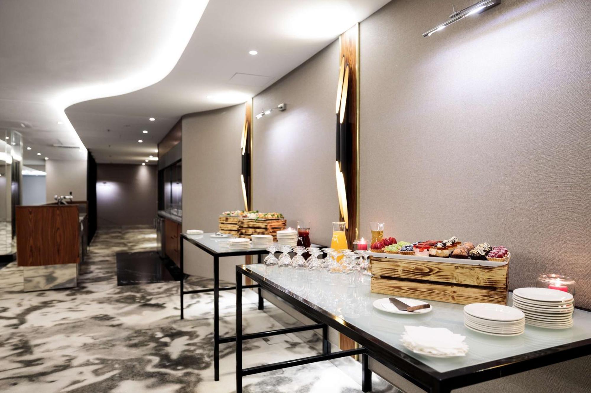 منتجع راديسون بلو سوينوجسي سفينويتشي المظهر الخارجي الصورة The photo showcases a modern, elegantly designed banquet or catering area. There are sleek tables set up, featuring a variety of food displays. One table appears to have a wooden crate filled with assorted fruits and pastries, while the other table s