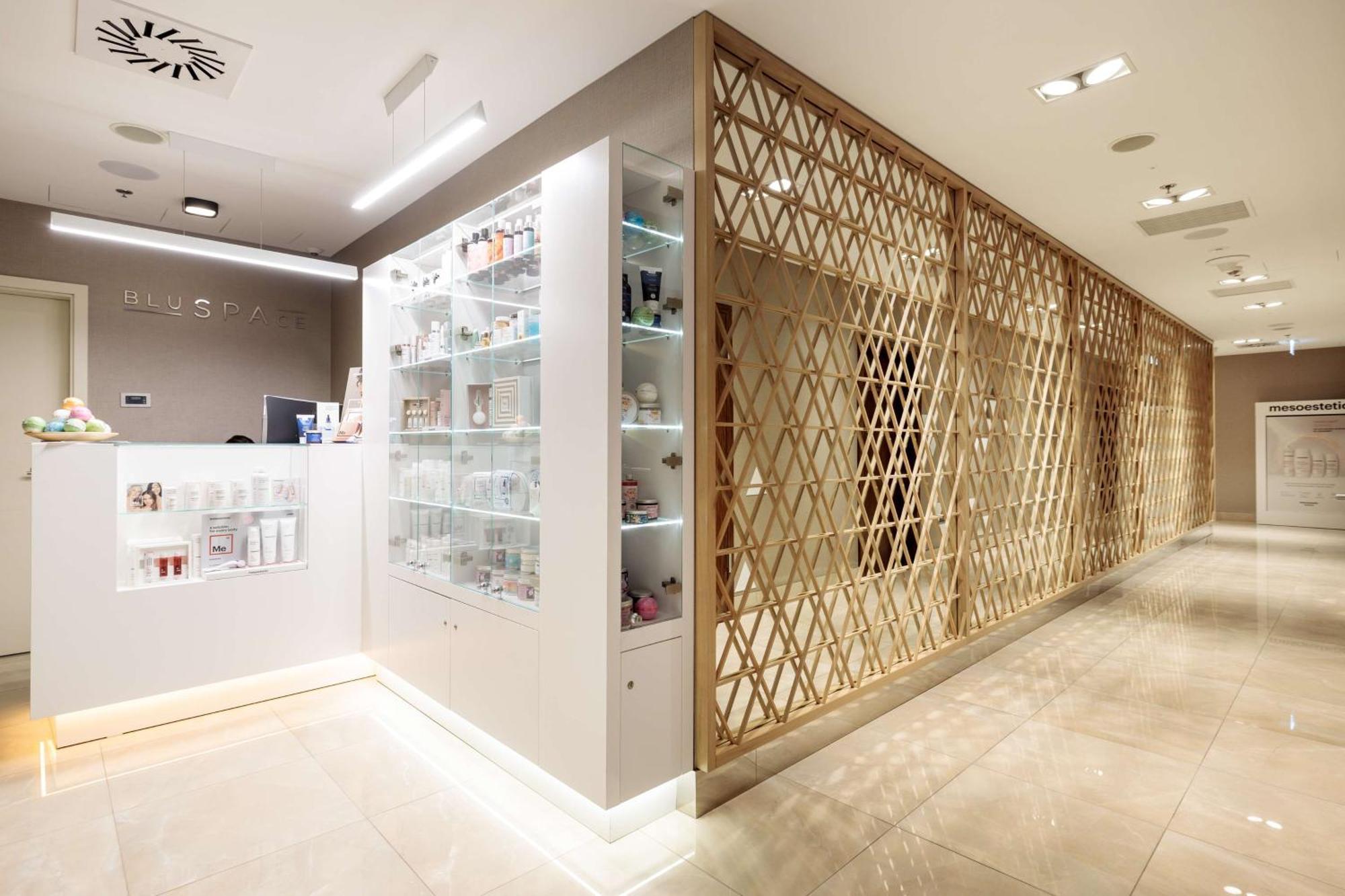منتجع راديسون بلو سوينوجسي سفينويتشي المظهر الخارجي الصورة The photo shows a modern interior, likely from a spa or skincare clinic. On the left, there is a reception area with a sleek white counter and an illuminated display showcasing various skincare products. The wall behind the reception features a glass