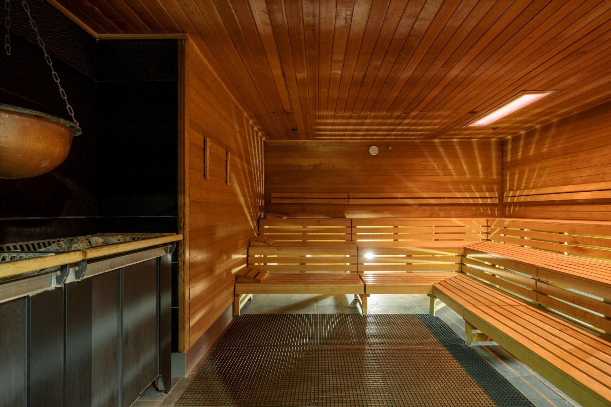 منتجع راديسون بلو سوينوجسي سفينويتشي المظهر الخارجي الصورة The photo shows the interior of a sauna. The walls and benches are made of wood, creating a warm and inviting atmosphere. There is a heater, likely for generating steam, and a metal rack connected to it, perhaps for holding stones or water. The desig