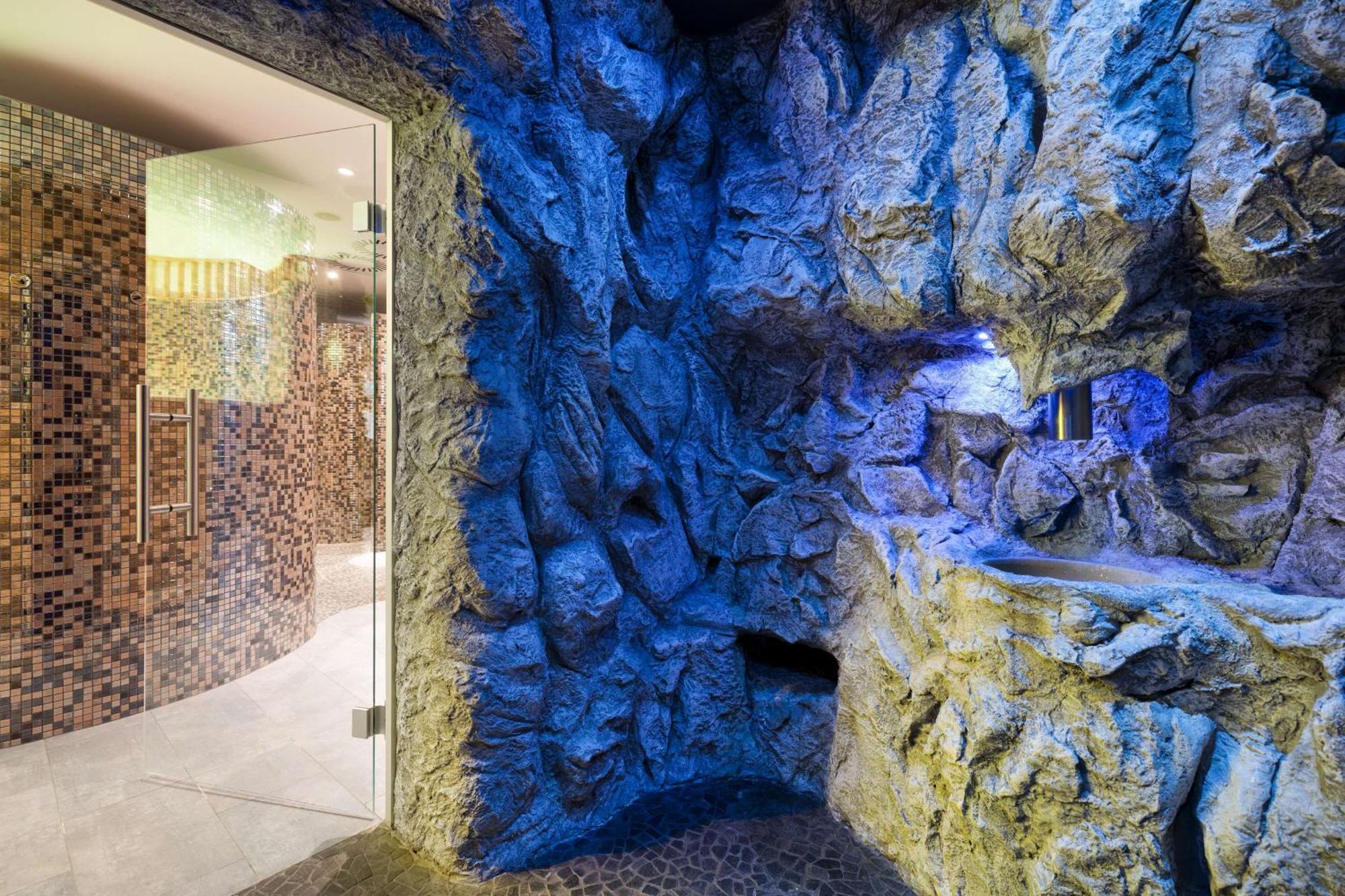 منتجع راديسون بلو سوينوجسي سفينويتشي المظهر الخارجي الصورة The photo shows a spa-like environment with a cave-like design. The walls are styled to resemble natural rock formations, featuring textures and colors that suggest a stone surface. Soft blue lighting highlights the contours of the rocks, creating a 