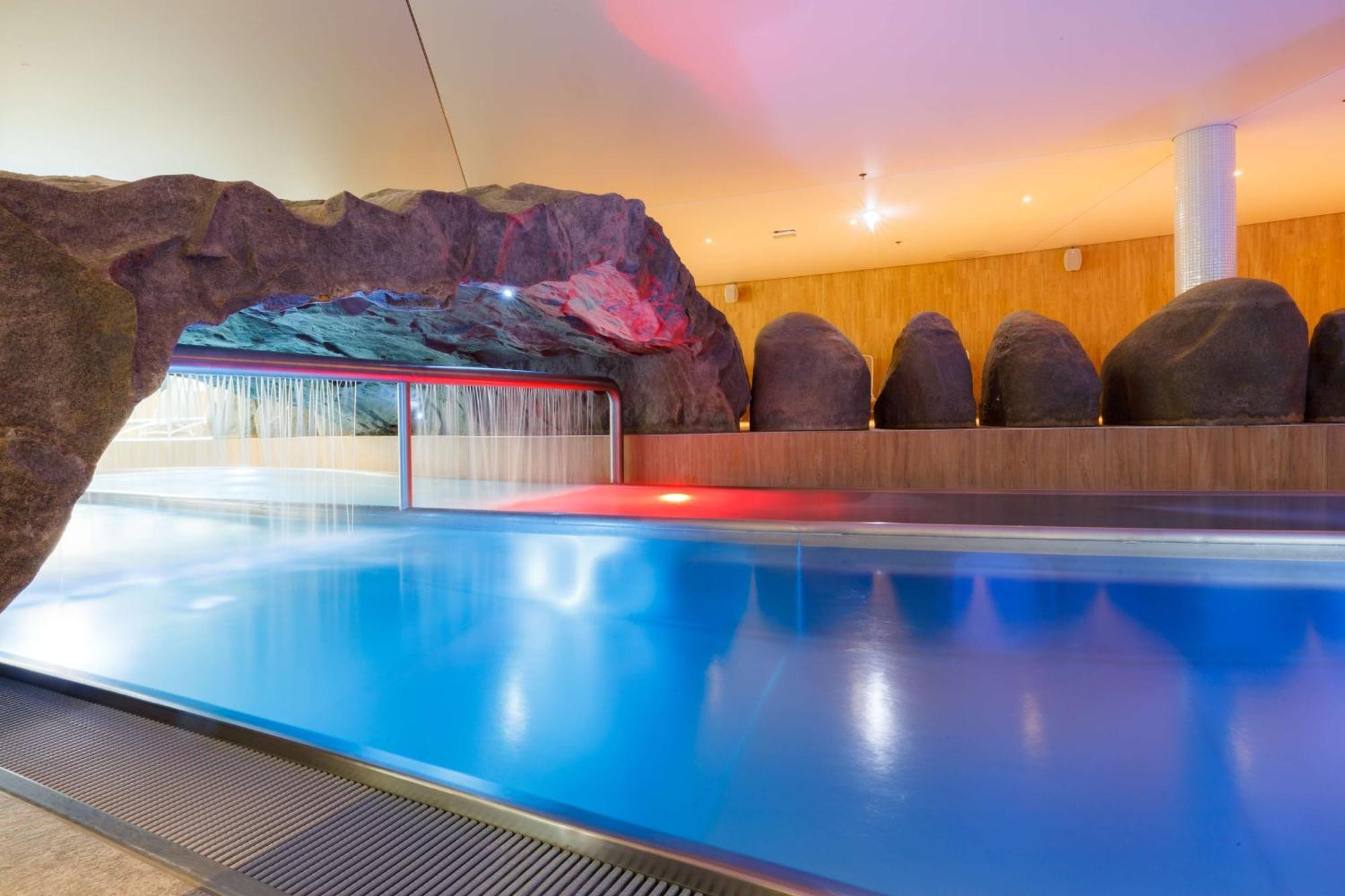 منتجع راديسون بلو سوينوجسي سفينويتشي المظهر الخارجي الصورة The photo shows a serene indoor swimming pool area. The pool has clear blue water, and there is a distinctive rock formation that resembles a cave on one side. Soft lighting enhances the atmosphere, casting a gentle glow across the space. In the back